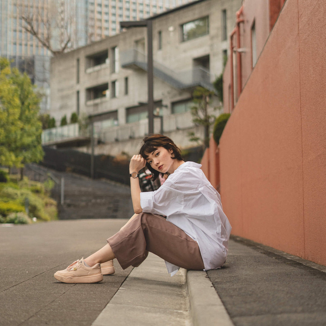 페어호이 나무 손목시계 Petite｜SAKURA를 착용하고 도로에 앉아 있는 흰 셔츠의 여자